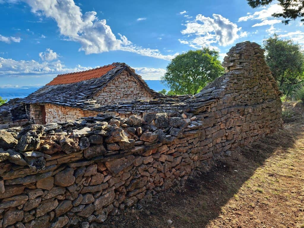 Dry-stone wall and stone roofs in Humac with the sea beyond