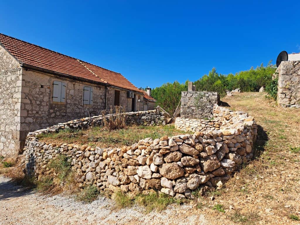 Langt steinhus bak en tørrmur i Gromin Dolac