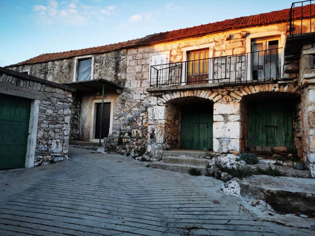 Stone houses with balconies along a lane in Gdinj