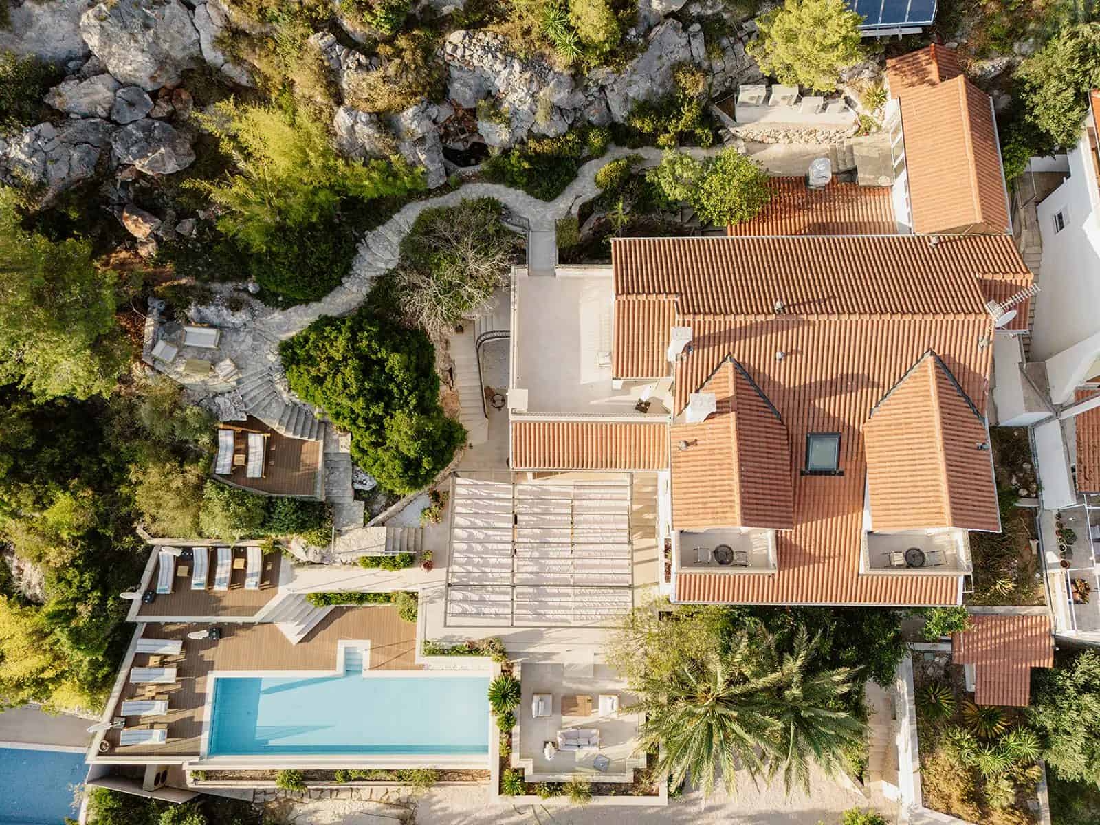 Villa Hvar Panoramic seen from the air — a long pool, a terraced garden and the tiled roofs of Hvar Town below it