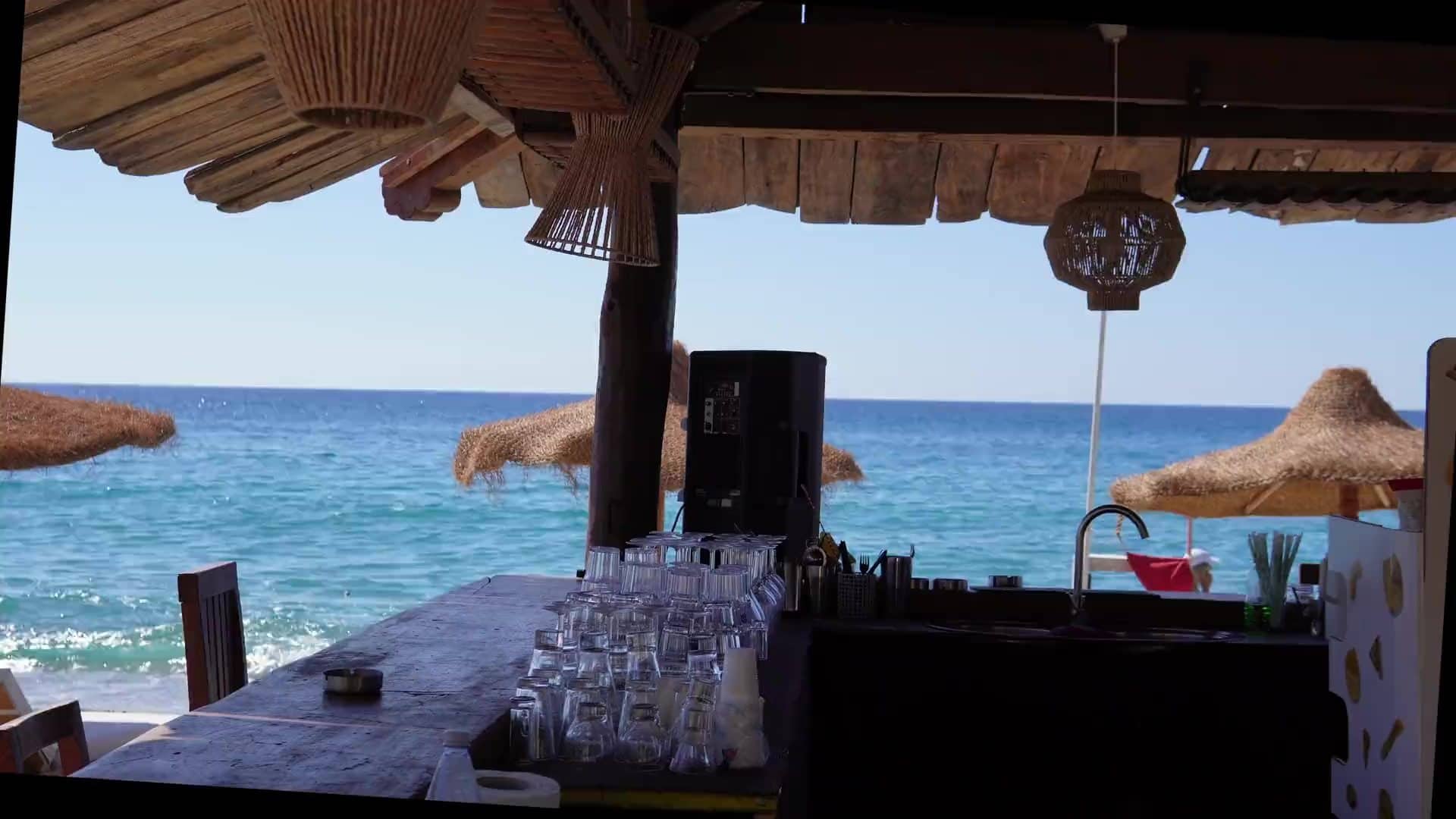 Beach bar on the shore near Hvar town at golden hour, with sunbeds and the sea beyond