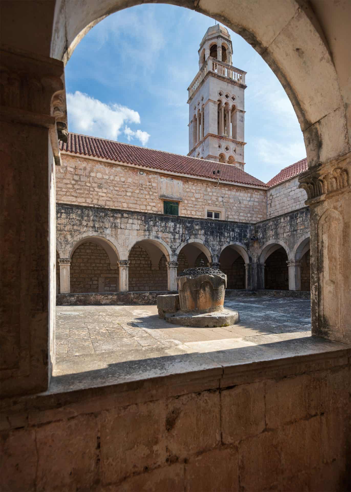 Stone arches and bell tower inside the cloister of the Franciscan monastery in Hvar