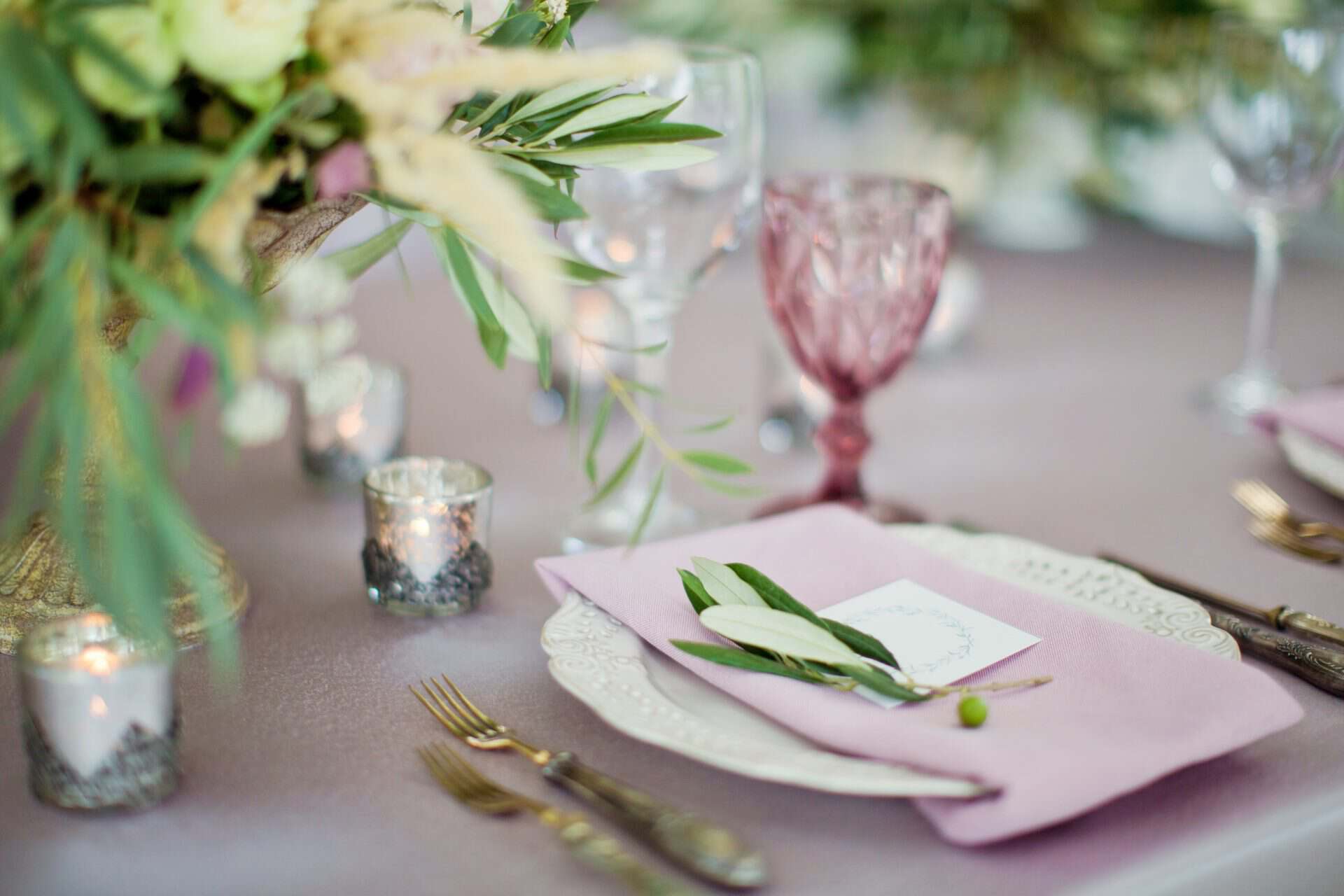 Table with wildflowers in glass jars and coloured glasses