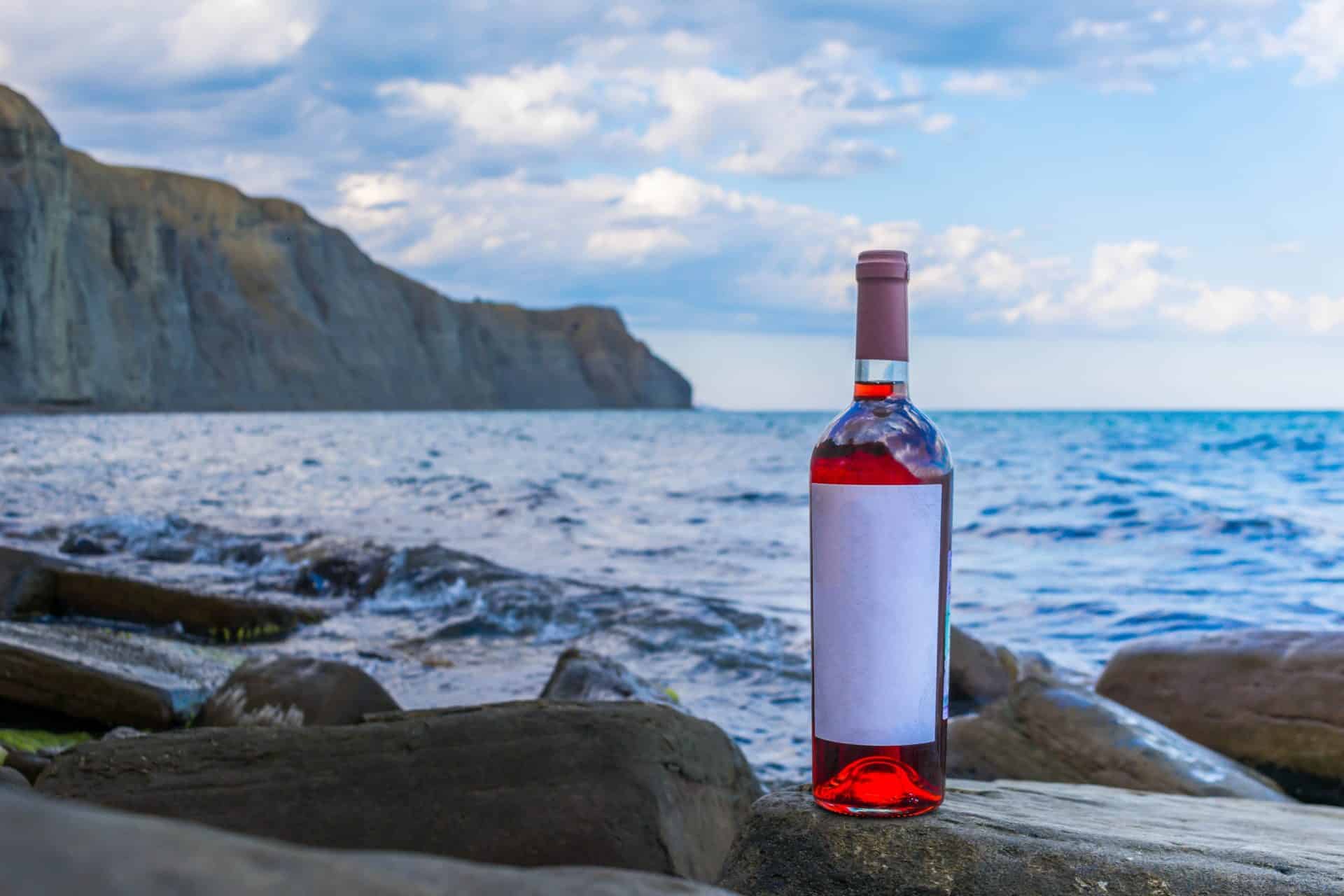 Rosé wine bottle on rocks by sea