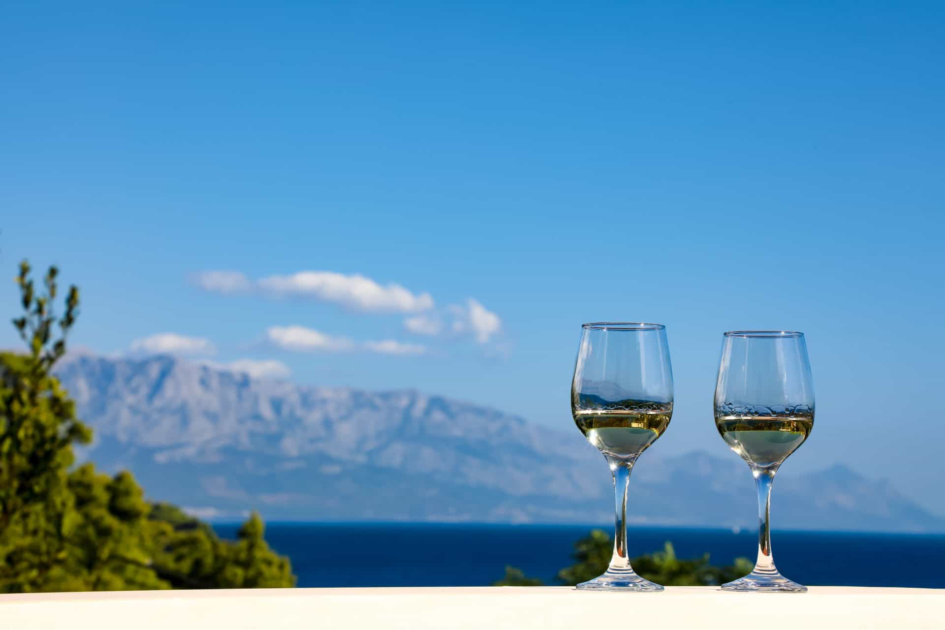 Two glasses of white wine with the Dalmatian coast behind