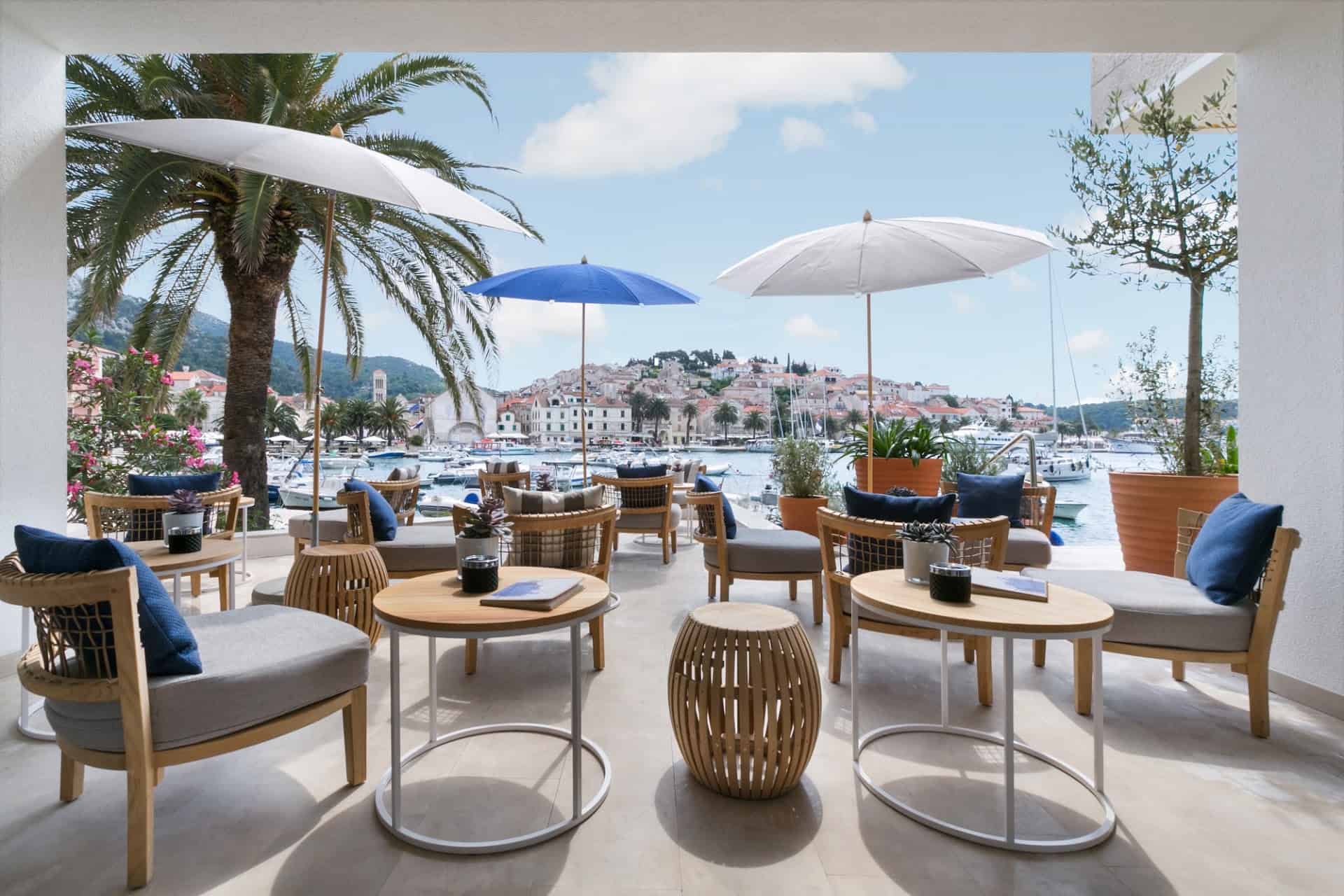 The rooftop terrace of the Adriana hotel, low chairs and parasols facing Hvar Town across the harbour